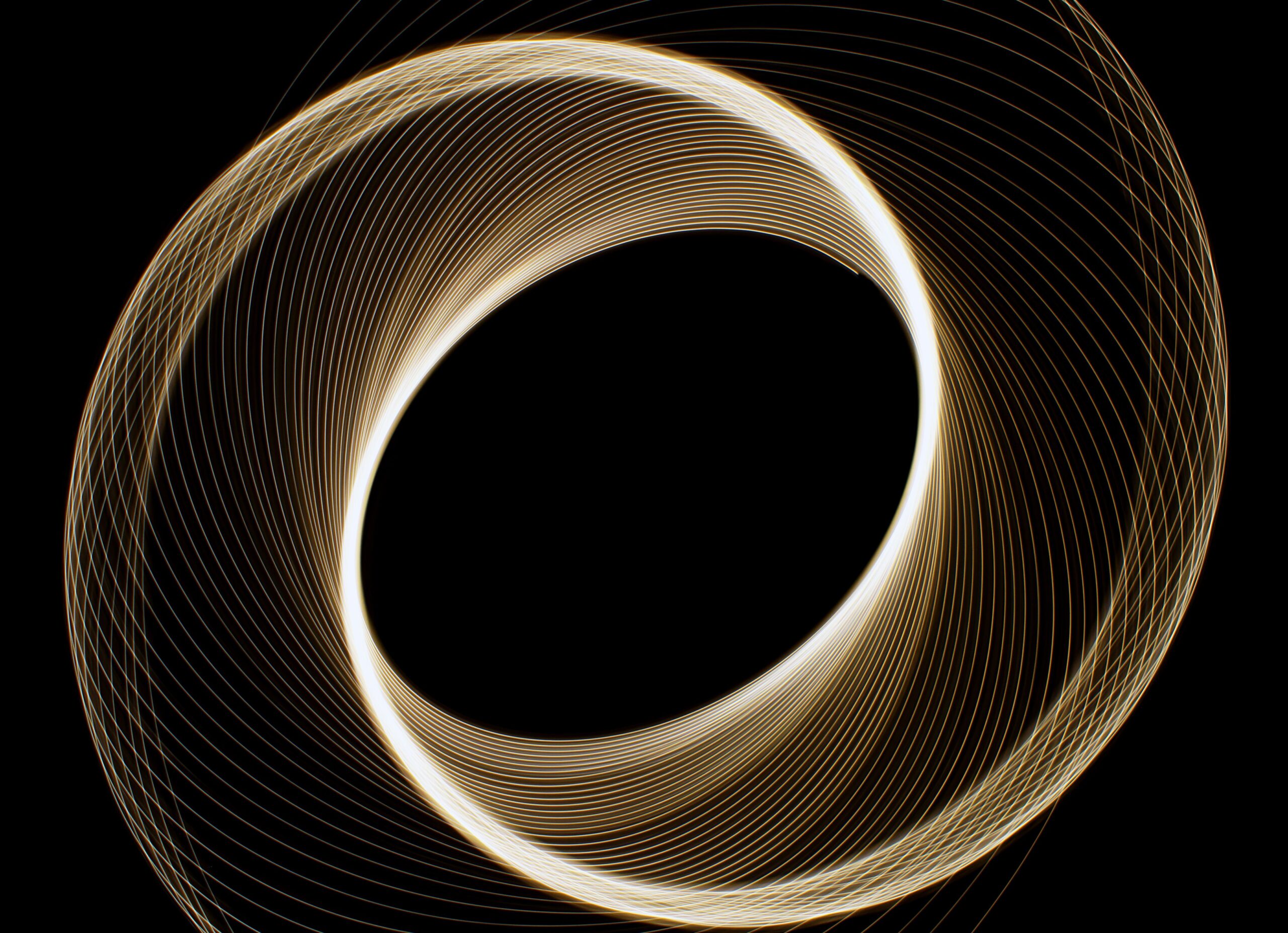 Dynamic light trails in circular form creating an abstract geometric pattern against a black background.